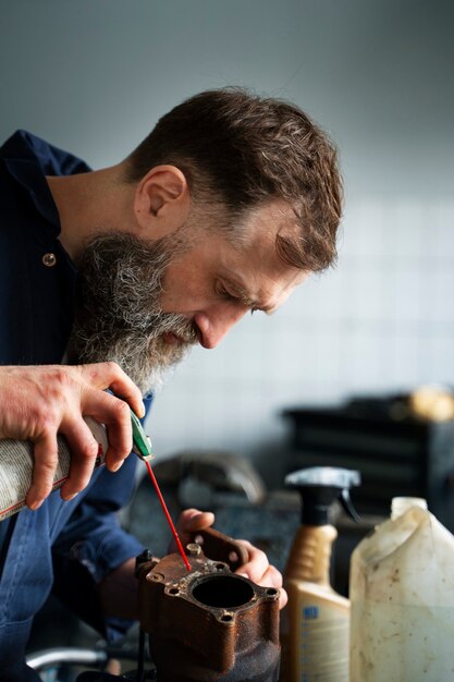 Mécanicien masculin travaillant dans un atelier de réparation automobile sur une voiture