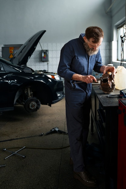 Mécanicien masculin travaillant sur la voiture dans l'atelier de réparation automobile