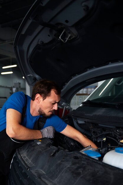 Mécanicien masculin travaillant sur la voiture dans l'atelier de réparation automobile