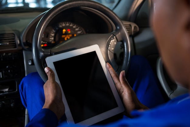 Photo gratuite mécanicien utilisant tablette numérique dans la voiture