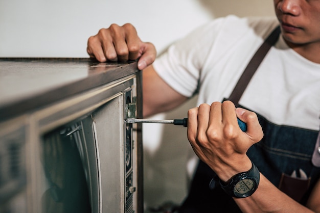 Le mécanicien utilise un tournevis pour serrer les vis du téléviseur.