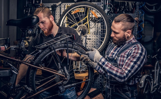 Mécanicien de vélos dans un atelier avec pièces de vélo et roue sur fond.