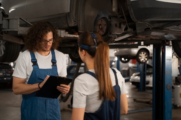 Photo gratuite mécaniciens masculins et féminins travaillant dans le magasin sur une voiture