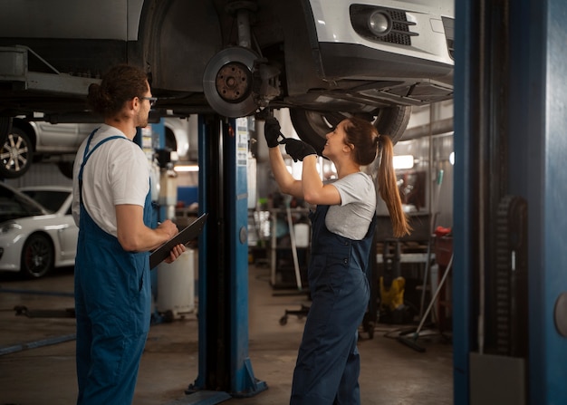 Photo gratuite mécaniciens masculins et féminins travaillant dans le magasin sur une voiture