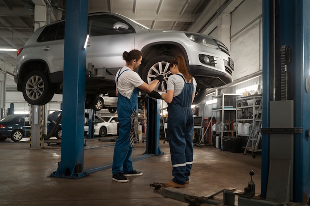 Photo gratuite mécaniciens masculins et féminins travaillant dans le magasin sur une voiture