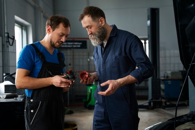 Photo gratuite mécaniciens masculins travaillant ensemble sur la voiture dans le magasin