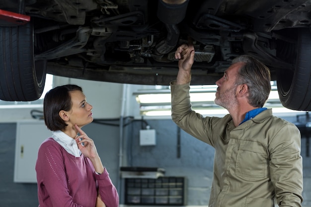 Photo gratuite mechanic montrant client le problème avec la voiture