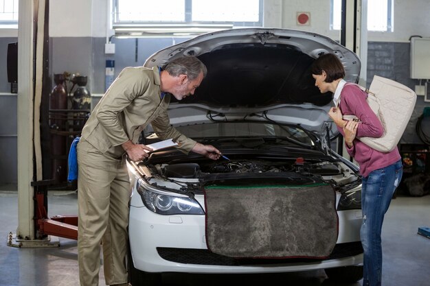 Mechanic montrant client le problème avec la voiture