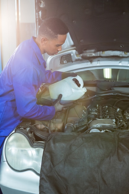 Mechanic verser de l&#39;huile lubrifiante dans le moteur de voiture