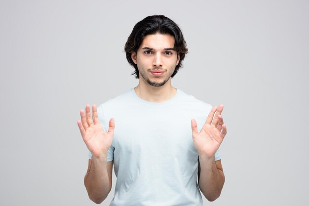 Mécontent jeune bel homme regardant la caméra montrant les mains vides isolé sur fond blanc