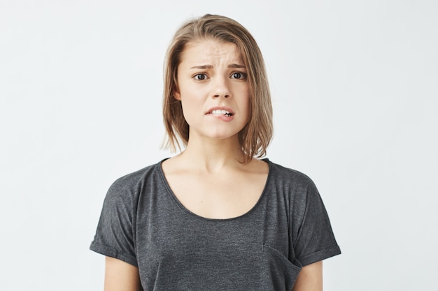 Mécontent jeune jolie fille honteuse se mordant la lèvre.