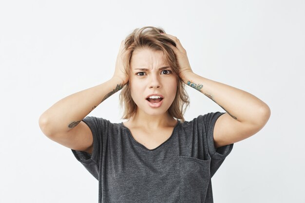 Mécontent jeune jolie fille honteuse tenant la tête.