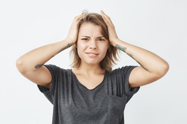 Mécontent jeune jolie fille honteuse tenant la tête.