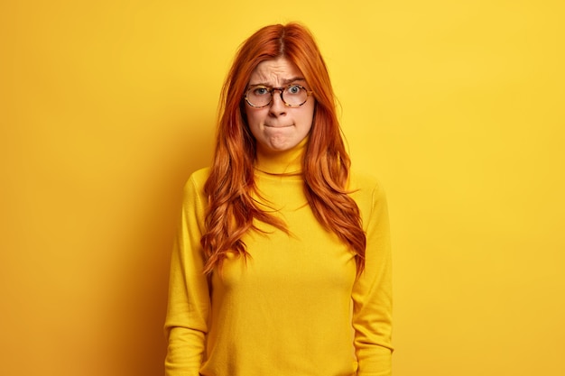 mécontent rousse femme européenne presse les lèvres et a une expression nerveuse porte des lunettes rondes occasionnels poloneck fait face à quelques problèmes.