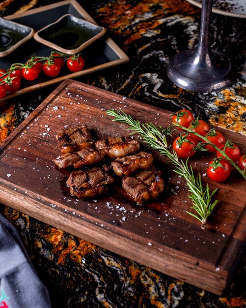 Médaillons de viande grillée servis avec brin de romarin et tomates