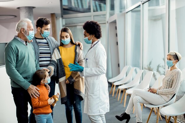 Médecin afro-américain parlant à sa famille élargie à la clinique médicale pendant la pandémie de coronavirus