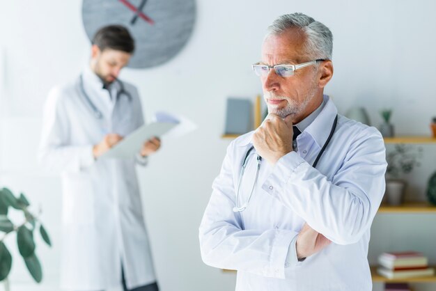 Médecin âgé pensant au bureau