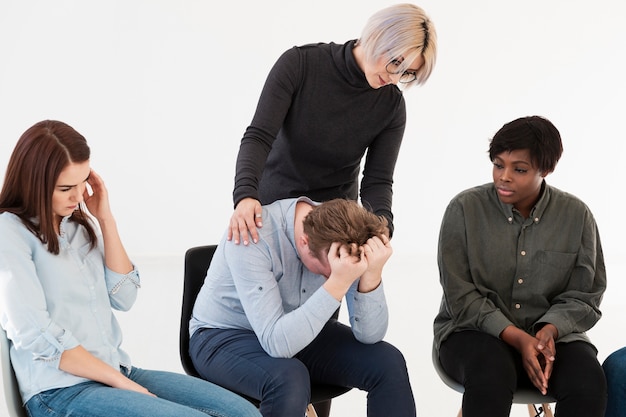 Médecin attentif consolant jeune homme