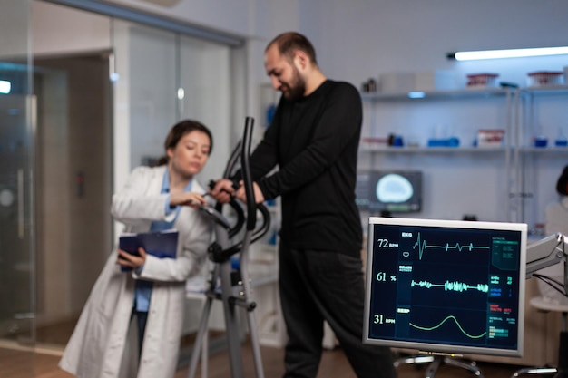 Photo gratuite médecin chercheur spécialiste discutant avec un sportif dans un équipement d'entraînement de gym surveillant l'endurance du corps pendant l'entraînement médical dans un laboratoire moderne. médecin chercheur analysant les données ecg