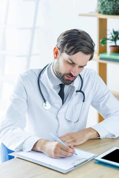 Médecin ciblé prenant des notes au bureau