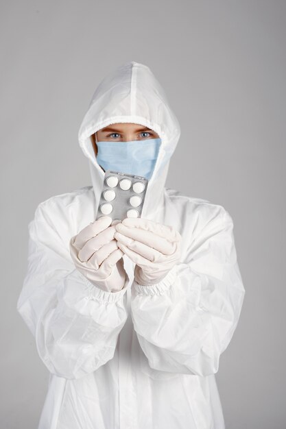 Médecin dans un masque médical. Thème du coronavirus. Isolé sur fond blanc. Femme avec des pilules.