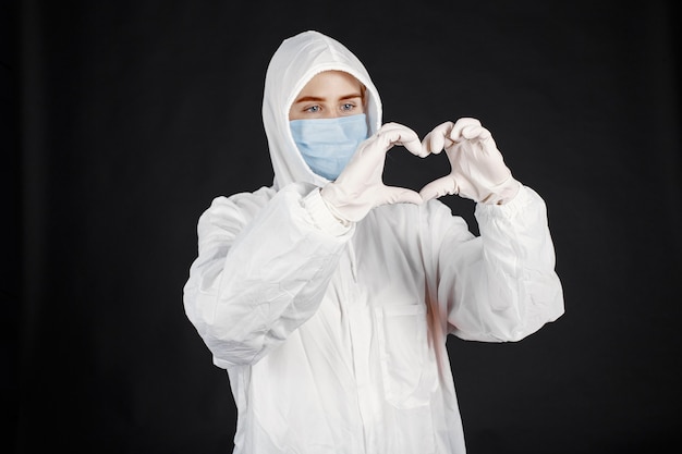 Médecin dans un masque médical. Thème du coronavirus. Isolé sur mur noir. Femme en tenue de protection.