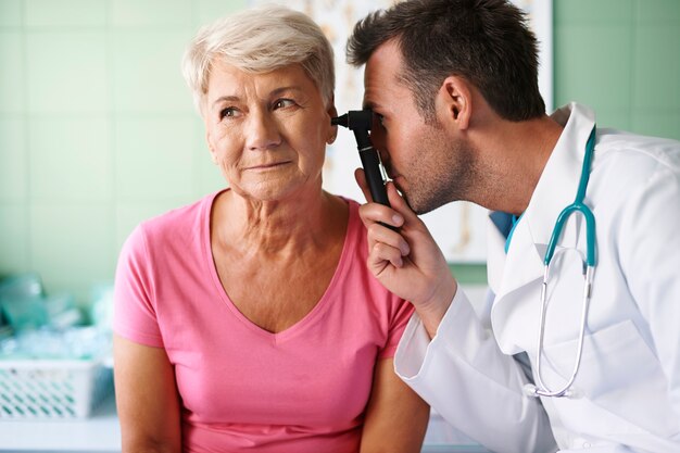 Médecin examinant l'oreille de la femme senior