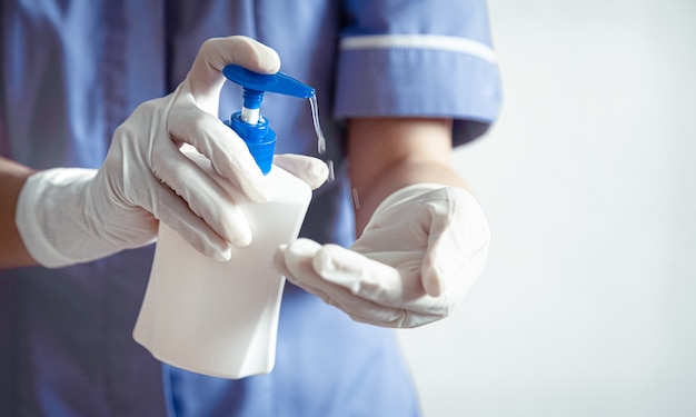 Le médecin en gants blancs utilise un désinfectant pour les mains contre la propagation du virus Corona covid-19.