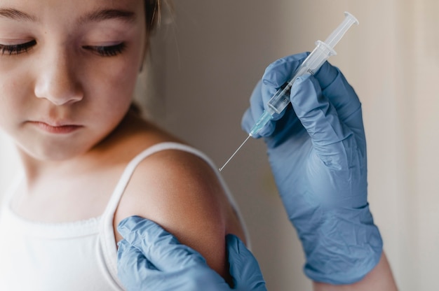 Photo gratuite médecin avec des gants donnant un vaccin au petit enfant