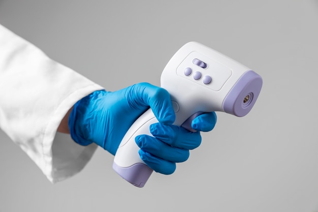 Photo gratuite médecin avec des gants tenant un thermomètre