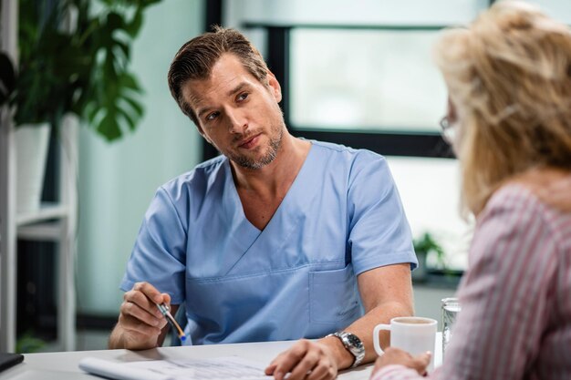 Médecin généraliste communiquant avec une femme lors du rendez-vous au cabinet du médecin