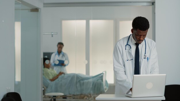 Médecin généraliste regardant un ordinateur portable moderne pour travailler sur le traitement médical et le système de santé. Médecin utilisant un appareil pour trouver des informations de contrôle pour soigner un patient atteint de maladie.