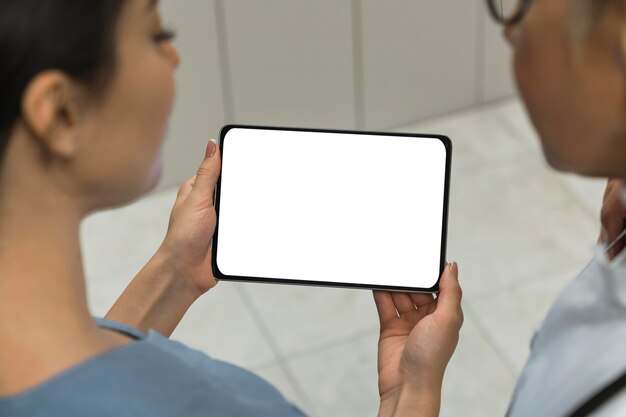 Médecin et infirmière regardant une tablette vierge
