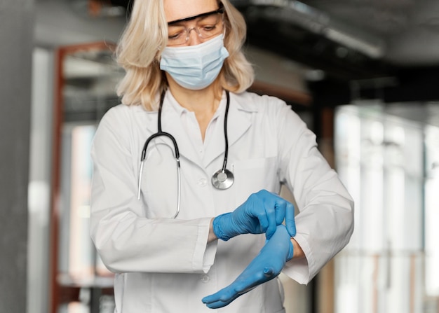 Photo gratuite médecin avec masque médical mettant des gants médicaux