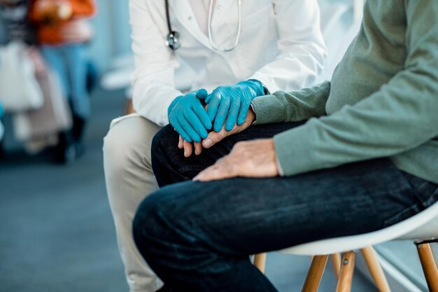 Médecin méconnaissable consolant un patient âgé dans la salle d'attente de l'hôpital