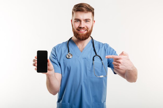 Médecin montrant le téléphone et souriant.