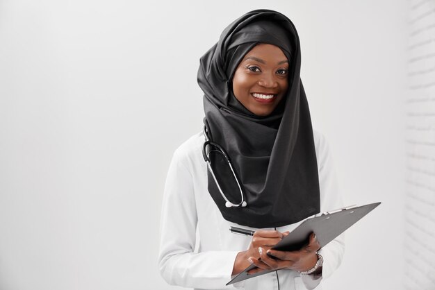 Médecin musulman avec stéthoscope tenant dossier et stylo