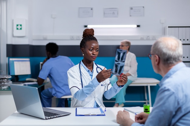 Médecin d'origine afro-américaine tenant un rayon x pour un vieux patient