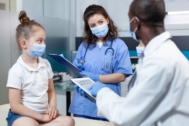 Médecin pédiatre afro-américain analysant l'expertise en matière de maladie à l'aide d'une tablette