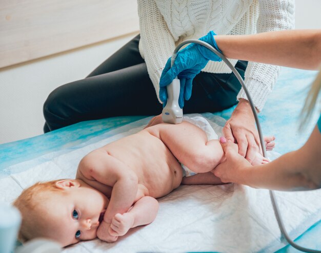 Osteopathe Faisant Une Evaluation De La Hanche Sur Un Patient Flechissant Sa Jambe Pour Verifier La Mobilite De L Articulation Et L Alignement Du Bassin Alors Qu Elle S Allonge Sur Un Canape Dans Sa Clinique