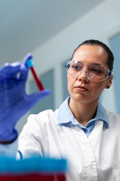 Médecin scientifique tenant un aspirateur de sang analysant pendant une expérience de biochimie dans un laboratoire hospitalier de microbiologie, femme chimiste développant un traitement de santé contre la maladie