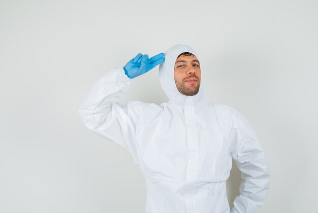 Médecin de sexe masculin pointant la main et les doigts à la tête en tenue de protection, gants et à la confiance