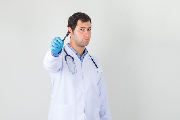 Médecin de sexe masculin pointant le stylo vers l'avant en blouse blanche, vue de face des gants.