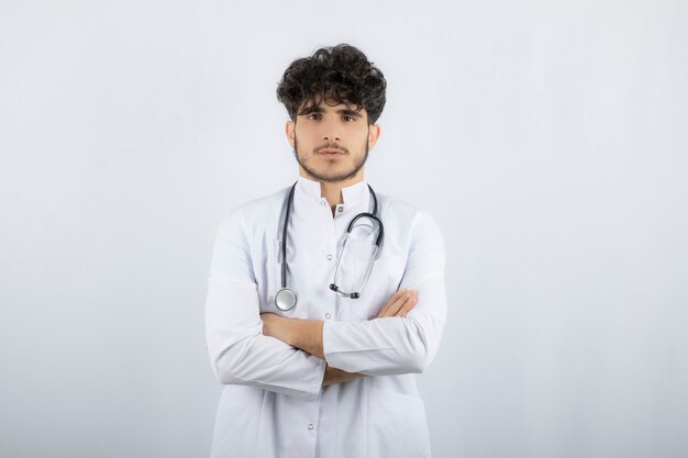 Médecin de sexe masculin avec un stéthoscope debout et regardant la caméra.