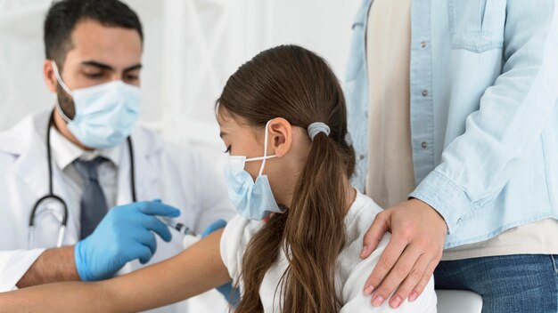 Médecin de sexe masculin vaccinant une fille