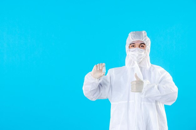 Médecin de sexe masculin vue de face en tenue de protection et masque sur le bleu