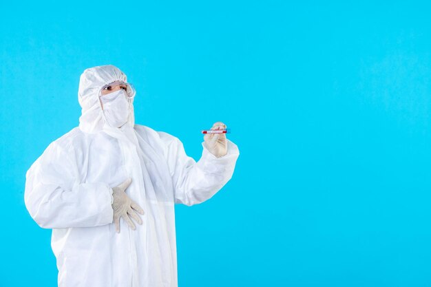 Médecin de sexe masculin vue de face en tenue de protection tenant une fiole sur bleu