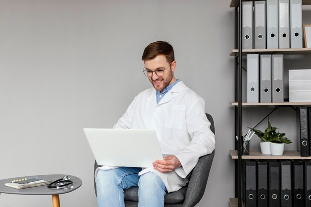 Médecin smiley coup moyen travaillant avec un ordinateur portable