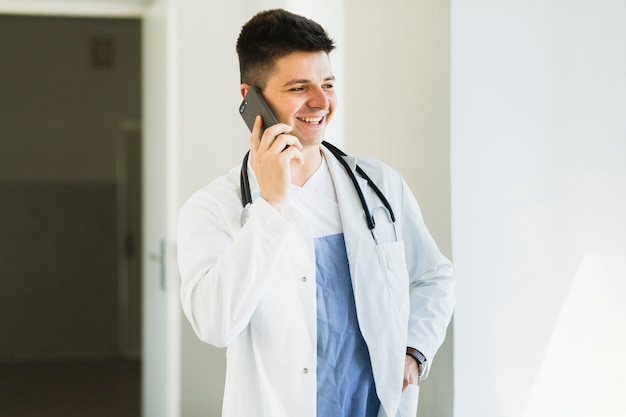 Médecin souriant faisant appel téléphonique