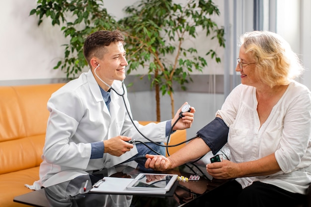 Médecin souriant mesurant la tension à un patient